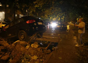 epa10756274 A man inspects a car damaged during a heavy storm in Belgrade, Serbia, 19 July 2023. A supercell storm has hit northern part of Serbia causing material damage.  EPA/ANDREJ CUKIC